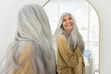Older dental implants patient in Tustin smiling in the mirror