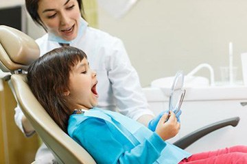 Dental team member and young patient smiling during children's dentistry visit