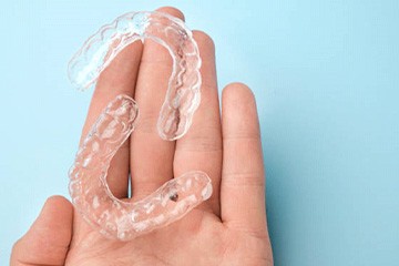 Hand holding clear aligners