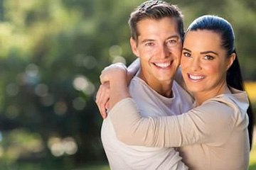 Man and woman sharing healthy smiles after dental crowns