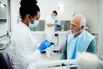 A dentist using a model to explain how dentures are made