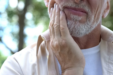 Man rubbing his aching jaw