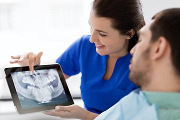 Dental team member and patient looking at digital x-rays