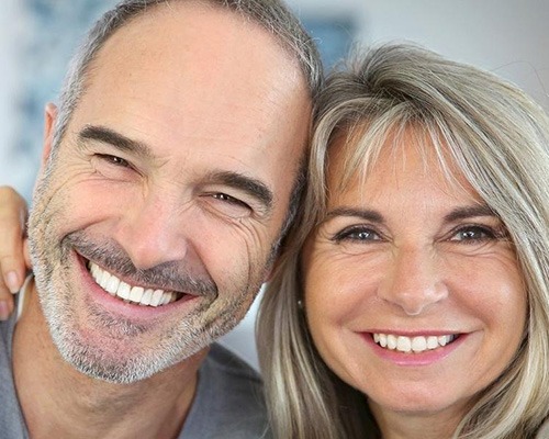 Man and woman smiling after tooth replacement with dental implants