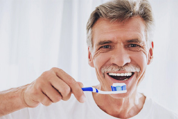 closeup of man brushing teeth after getting dental implants in Tustin