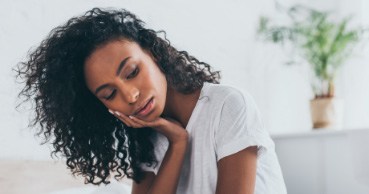 Woman holding her cheek with pain before emergency dentistry