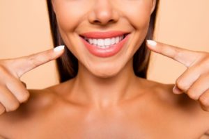 Woman pointing towards her smile.