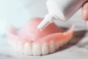 Cream denture adhesive being applied to denture