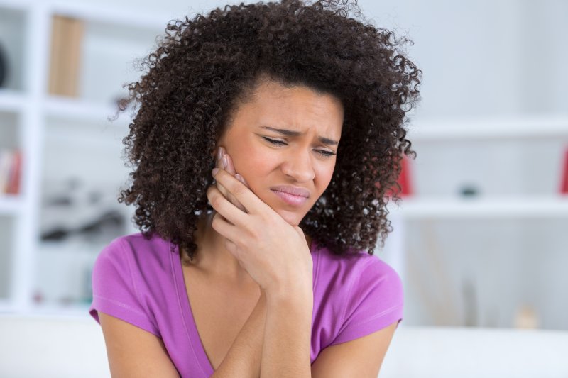 Patient holding their cheek due to dental emergencies