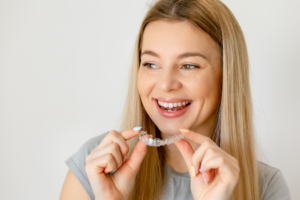 a patient smiling and holding their Invisalign aligner