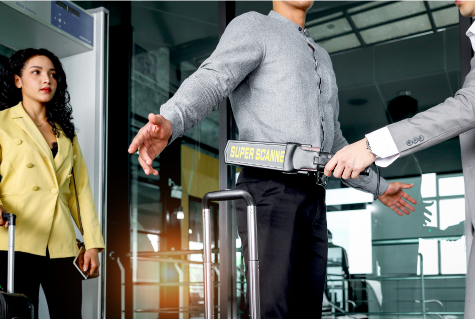 Passenger getting scanned with metal detector wand in TSA line